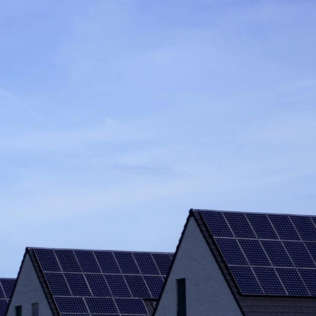 Modern Belgian houses with solar panels on rooftops under a clear blue sky.